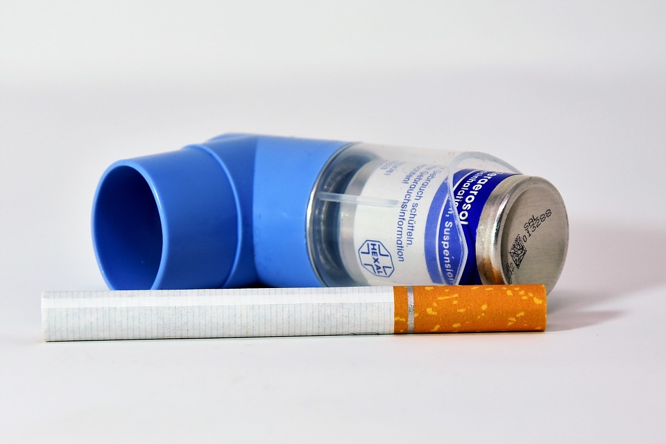 a close up shot of a cigarette laying next to an inhaler. implies cause and effect.