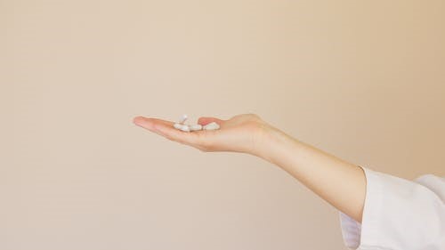 A person holds up a palm-full of pills that are necessary for their health.