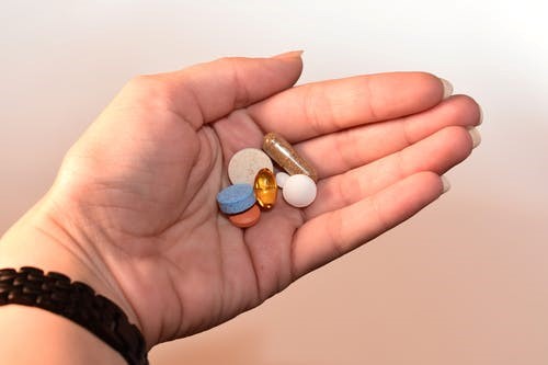 Different pills and medications held in someone’s palm.