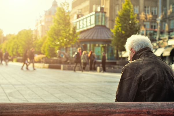 An old person sitting on a bench alone