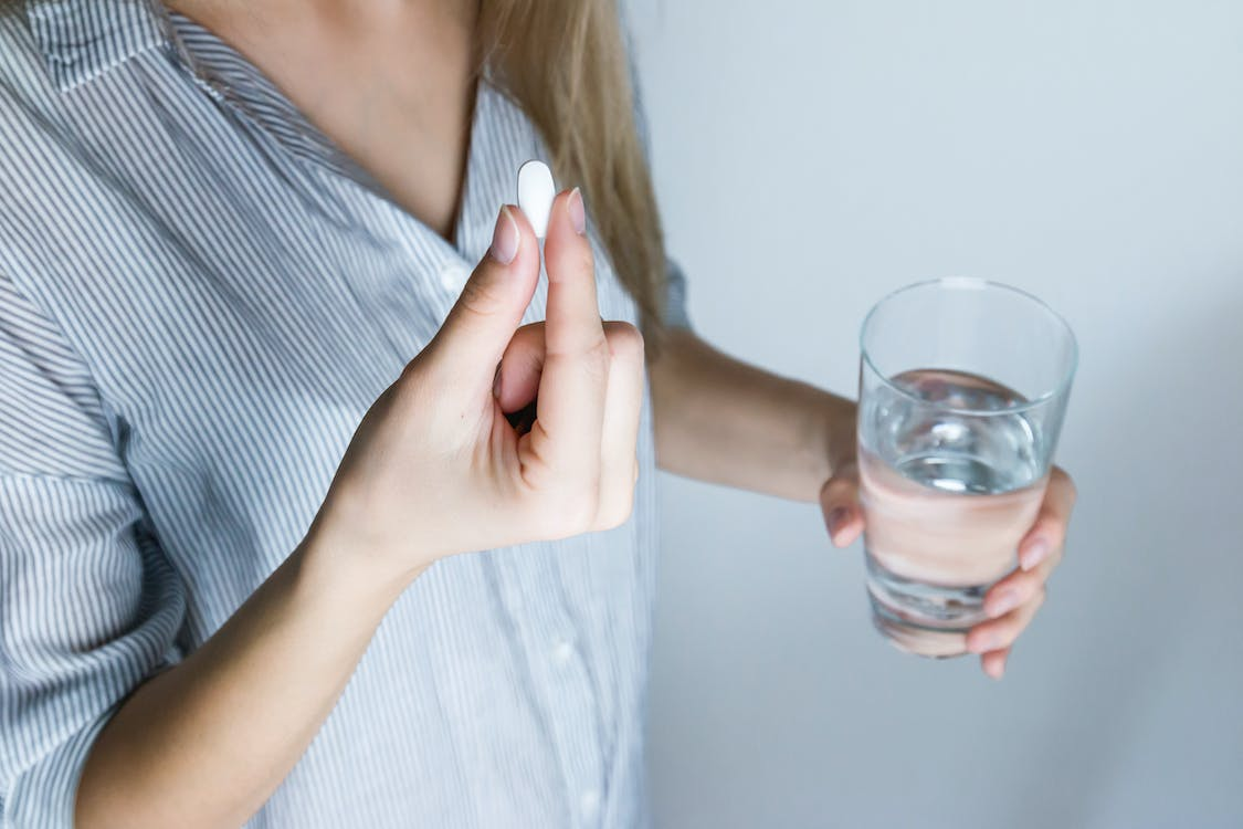 a person holding a pill and glass of water