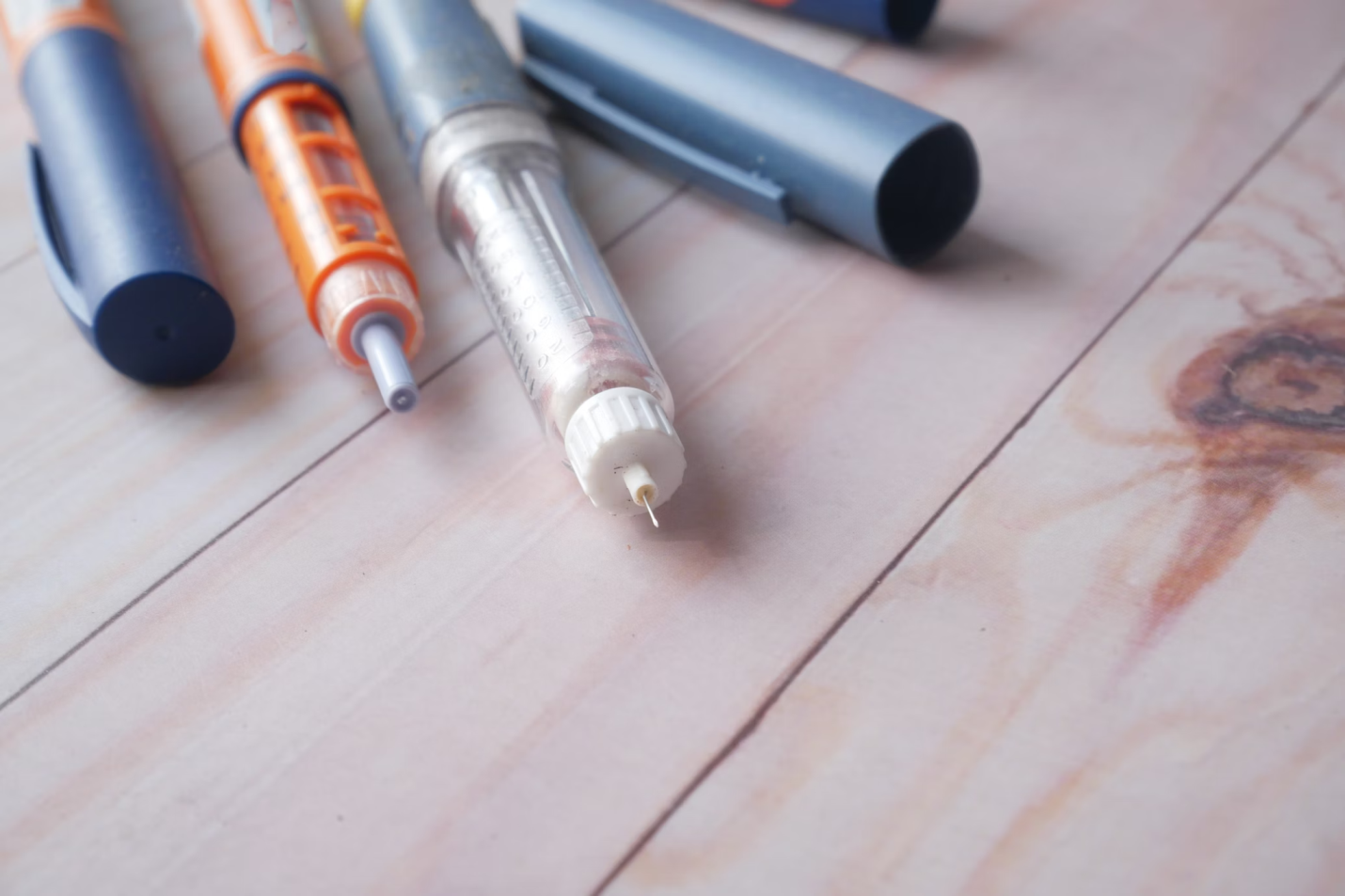 A photo showing insulin pens resting on a wooden surface