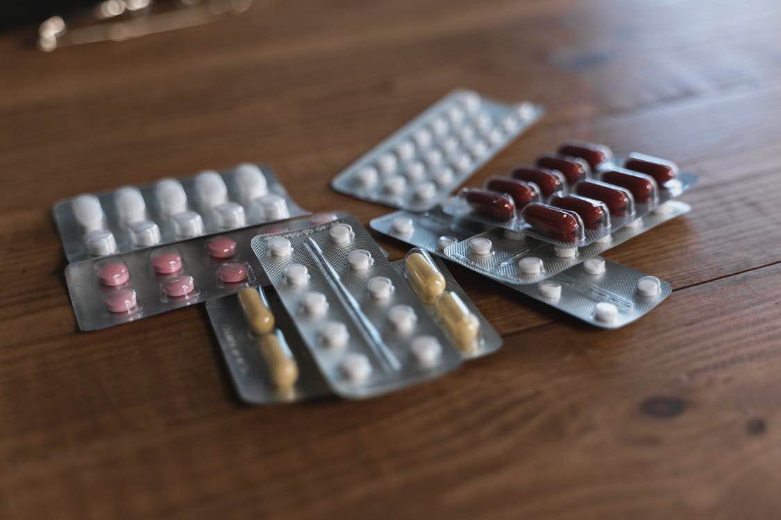 The image shows several blister packs of different medications with various colors and shapes of pills.