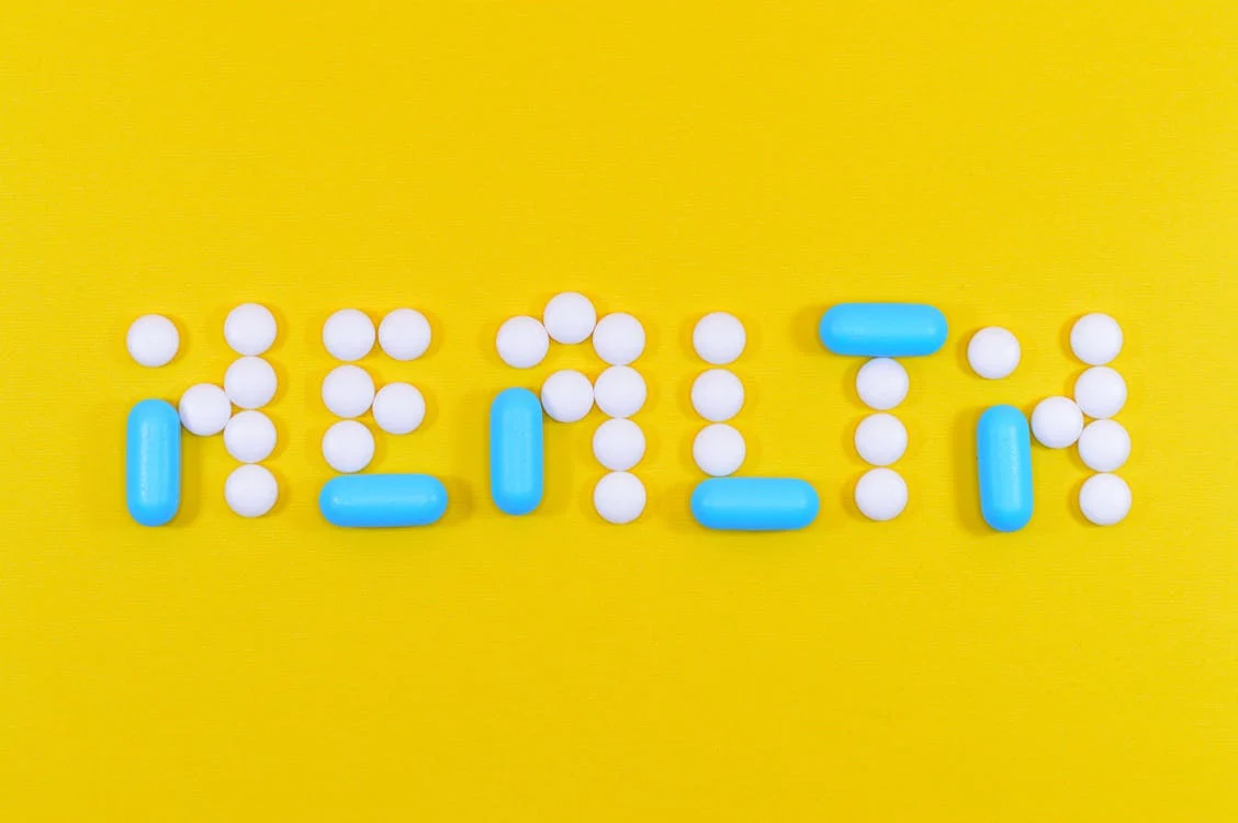 White and blue pills with a health letter cutout.