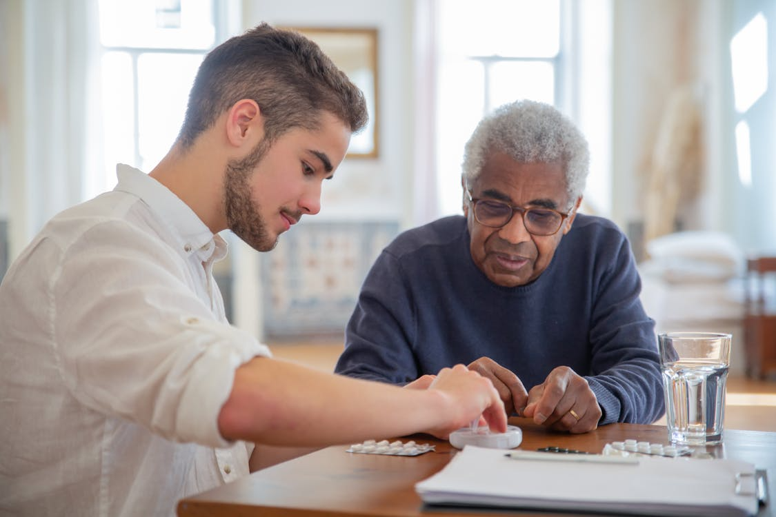 Younger caregiver assisting an older adult with organizing medication